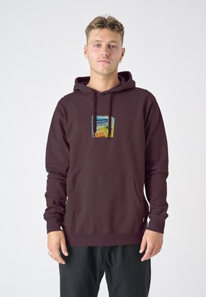 Maroon hoodie with a front pocket, featuring a colorful graphic patch. Made of cotton with a soft texture and fitted sleeves.