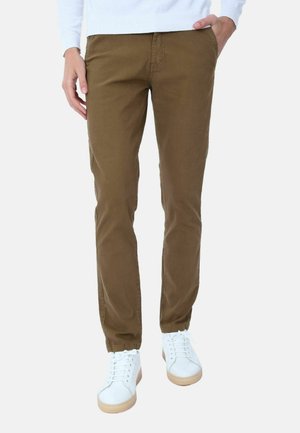 Chinos in cotone marrone con una vestibilità dritta, dotati di tasche frontali. Abbinati a sneakers bianche e a un maglione azzurro chiaro.