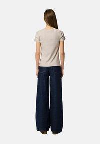 Lysegrå ribbet t-shirt med korte ærmer, parret med højtaljede, brede mørkeblå denimbukser, der har baglommer og en afslappet pasform.