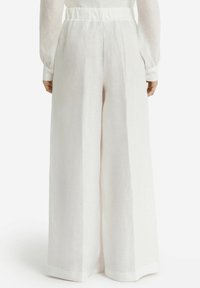 Pantalons larges en lin blanc avec une taille haute. Présente une texture lisse et un design fluide, avec des coutures nettes et sans embellissements visibles.