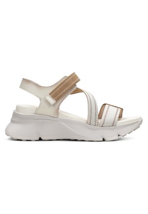 Sandales sportives blanches et beige avec deux larges brides, matériau texturé, semelle rembourrée avec un design ondulé et une semelle antidérapante.