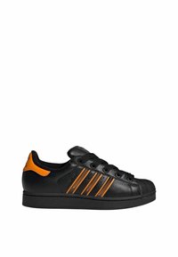 Baskets en cuir noir avec des bandes et un talon orange, lacets noirs, et bout en caoutchouc texturé noir sur fond blanc.