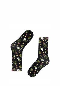 Czarne skarpetki z świątecznym wzorem, na którym znajdują się białe kwiaty, zielony ostrokrzew, cukierki w kształcie laski oraz złote gwiazdy na ciemnym tle.