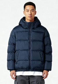 Giacca a vento imbottita blu navy con cappuccio, caratterizzata da un design trapuntato, polsini elasticizzati e orlo inferiore elasticizzato. Include tasche laterali e chiusura centrale con cerniera.