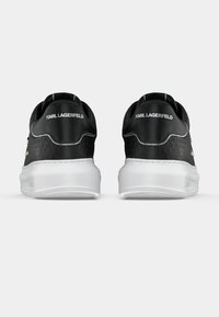 Črni teniski z teksturiranim materialom. Bel podplat, izvezen logotip na peti in gladki kontrastni poudarki. Minimalistična zasnova.