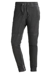 Svarta joggingsbyxor i en bomullsblandning, med dragkedjefickor, ribbad fåll och texturerade paneldetaljer på låren.