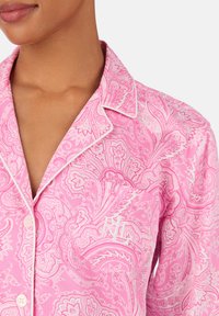 Haut de pyjama à motif paisley rose avec passepoil blanc, doté d'une poche avec le monogramme "RL", fabriqué en tissu doux. Design à boutons.