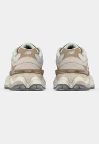 Pantofi sport bej și gri deschis cu partea superioară din piele întoarsă texturată, accente din plasă și o talpă voluminoasă, segmentată. Prezintă un călcâi întărit.