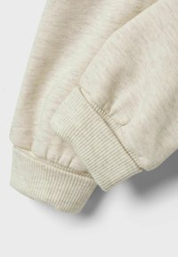 Beige Baumwoll-Sweatshirt mit Detail an den Ärmeln, das gerippte Bündchen, eine weiche Textur und ein dezentes Melange-Muster für zusätzliche Tiefe aufweist.