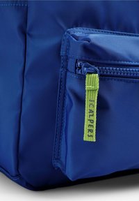 Bolsa de nylon azul con una superficie texturizada, que cuenta con un bolsillo frontal con cremallera y una etiqueta de tirador de cremallera de tela verde etiquetada como "SCALPERS."