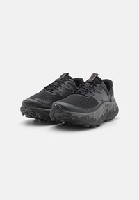 Zapatillas de correr negras con parte superior de malla y suela de goma texturizada. Diseño redondeado, puntera reforzada y sistema de cordones minimalista.