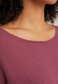 Mauve ribbed knit -paita, jossa on leveä pyöreä pääntie. Kangas on pehmeää ja siinä on hienovaraisia vaihteluita ribbikuviossa.
