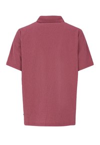 Camisa polo de manga corta en burdeos rojizo con un tejido texturizado, que presenta un cuello clásico y un dobladillo recto, sin logotipos visibles.