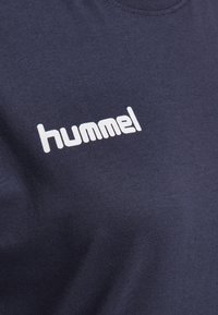 Camiseta de algodón azul marino con un logo blanco de "hummel", cuello redondo y textura suave.