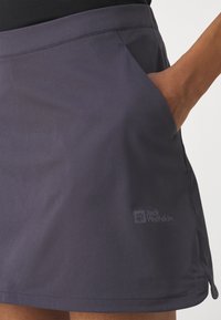 Donkergrijze buitenschoenrok met een gladde textuur, zijzak en Jack Wolfskin-logo, ontworpen voor comfort en bewegingsvrijheid.