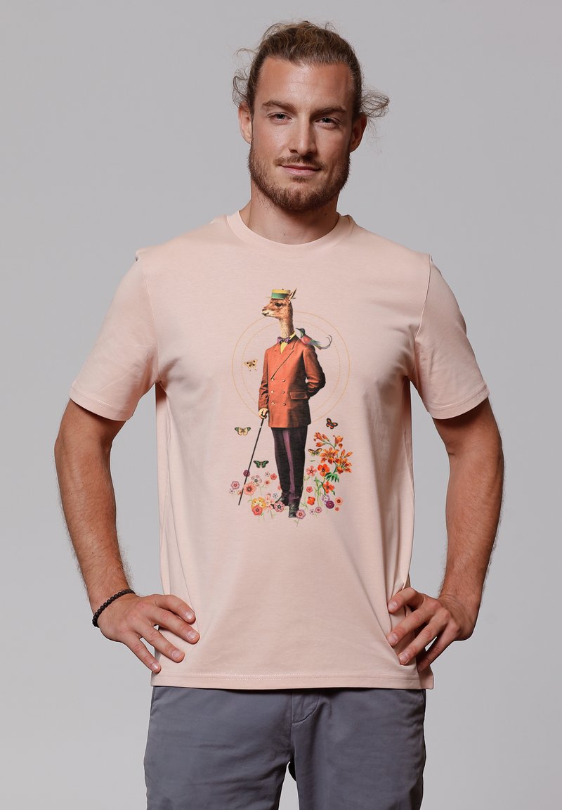 Hellrosa T-Shirt mit einem illustrierten Giraffen in einem braunen Anzug und Zylinder, umgeben von Blumen und Schmetterlingen. Kurzarm, Rundhalsausschnitt.