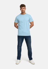 Lyseblå kortermet T-skjorte med rund hals, kombinert med mørk denimjeans. Sko fullfører det uformelle antrekket.