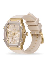 Reloj dorado y plateado con cara rectangular, correa de silicona crema, tres subesferas y una banda texturizada. Cuenta con un diseño de bisel distintivo.