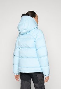 Donsjack in lichtblauw, met een capuchon, horizontaal gestikte ontwerp en knoopsluiting details bij de mouwuiteinden.