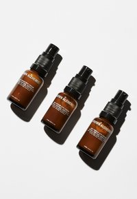 Tre bruna glasflaskor med spray, var och en med en svart pump och silverdetaljer. Etiketterna har vit text som beskriver produktinformationen.