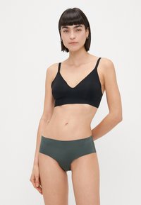 Svart trådlös bralette med V-necksdesign och justerbara band, tillsammans med sömlösa gröna trosor. Båda plaggen har en slät yta.