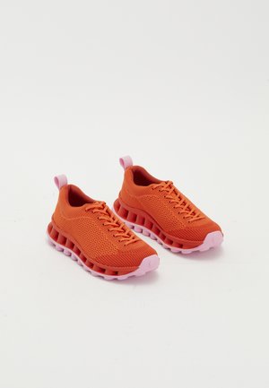 Sneaker in strahlendem Orange mit atmungsaktivem Mesh-Obermaterial, rosa Sohle mit einer einzigartigen tubularen Form und Zuglasche an der Ferse für ein bequemes Anziehen.