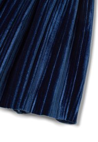 Tessuto piegato in velluto blu navy con una texture morbida, caratterizzato da strisce verticali e una finitura liscia che mette in risalto luci e ombre.