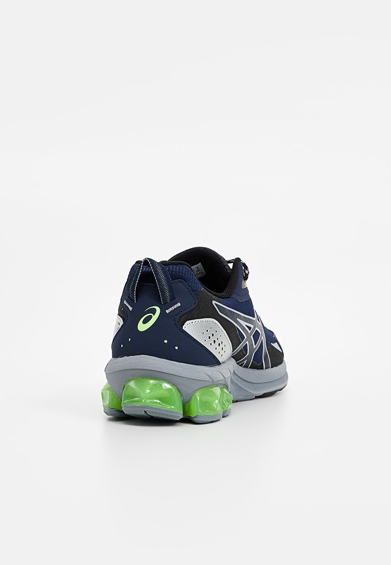 Scarpa da corsa blu navy con accenti grigi, neri e bianchi, dotata di una suola ammortizzata verde neon e di un tassello sul tallone.