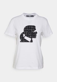 Camiseta de algodón blanca con un destacado gráfico de perfil en blanco y negro, con un patrón texturizado en la silueta. Manga corta y cuello redondo.
