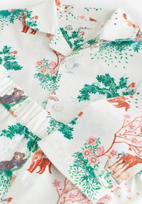 Valge puuvillane pluus, millel on roheline lehtede print ja loomade ning lillede illustratsioonid. Sisaldab kraega kaelust ja nööbikinnitust.