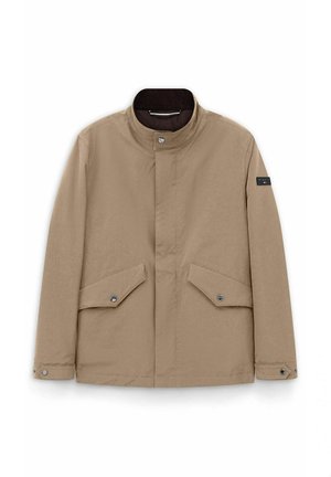 Beige Herrenjacke mit Stehkragen, vorne mit Druckknöpfen zum Schließen, zwei aufgesetzten Taschen mit Klappen und Druckknöpfen sowie einem Logo-Patch am linken Ärmel.