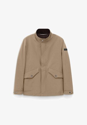 Beige Herrenjacke mit Stehkragen, vorne mit Druckknöpfen zum Schließen, zwei aufgesetzten Taschen mit Klappen und Druckknöpfen sowie einem Logo-Patch am linken Ärmel.