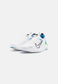 White athletic shoes with textured fabric, black and blue accents, a green heel counter, and a rubber sole with a low-profile design.