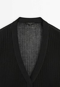 Schwarzer gerippter Cardigan mit V-Ausschnitt. Das Innenfutter weist dezente vertikale Streifen in einer kontrastierenden Farbe auf.