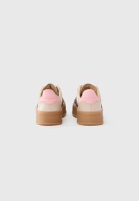 Sneakers featuring a beige and pink synthetic upper, a brown rubber sole, and a smooth texture with subtle branding on the heel.