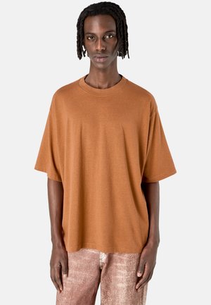 Brun oversize t-shirt i mjukt tyg, med rund halsringning och lösa ärmar. Bärs med ljusa, texturerade byxor.
