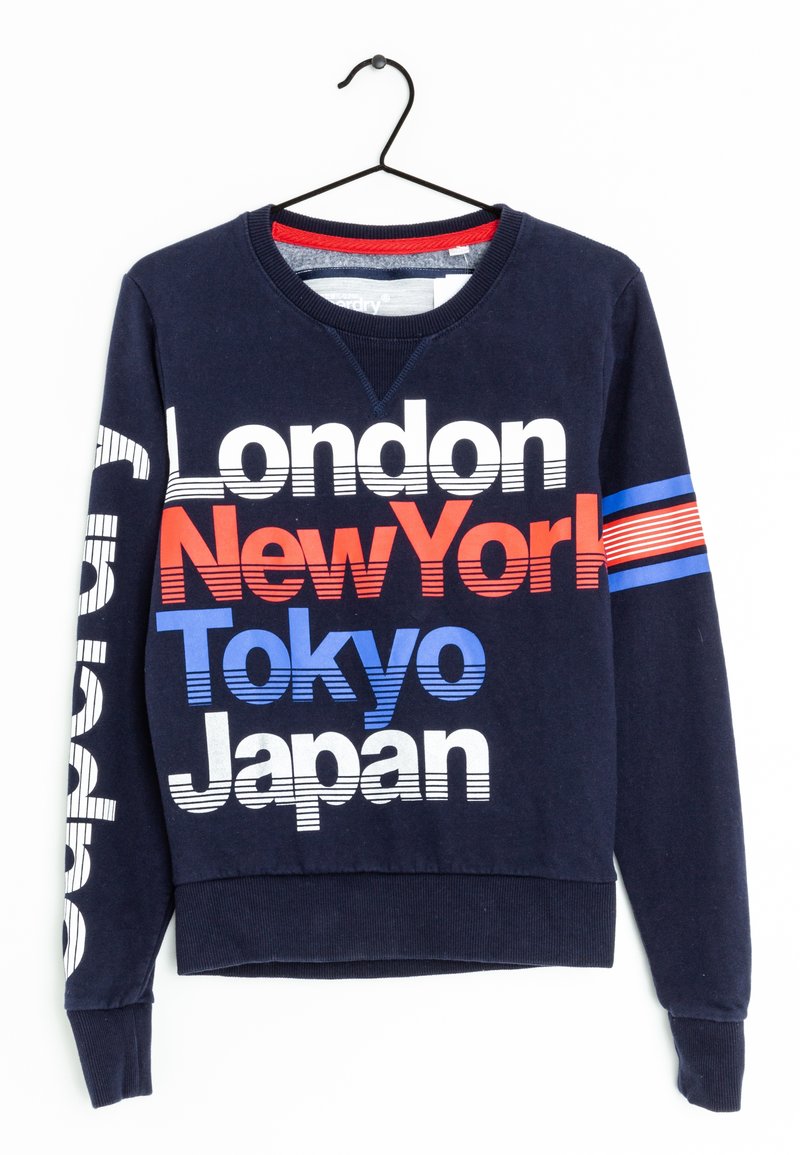 Sudadera navy con cuello redondo, que presenta un texto audaz en blanco, rojo y azul: "Londres", "Nueva York", "Tokio" y "Japón". Rayas horizontales en la manga.