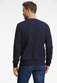 Laivastonsininen neulottu pyöreäkauluksinen paita, jossa on tekstuuri kuvio, resorit hihansuissa ja helmassa. Yhdistetty sinisiin farkkuihin, joissa on kontrastivärinen ompelu.