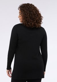 Svart långärmad topp med rundad nederkant, som har en slät textur och en diskret V-ringning baktill. Inga synliga mönster eller utsmyckningar.