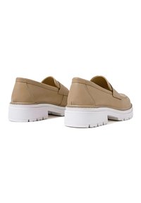 Scarpe slip-on beige realizzate in pelle liscia, con una suola spessa bianca, punta rotonda e dettagli di cucitura minimi sui lati.