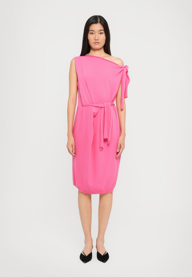 Rochie fucsia cu un umăr, realizată dintr-un material moale și texturat, având un accent legat la umăr și un cordon în talie, terminându-se deasupra genunchiului.