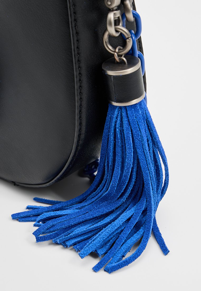 Sac en cuir noir avec un pompon en daim bleu bien visible, fixé par un fermoir en métal argenté avec un détail en chaîne.