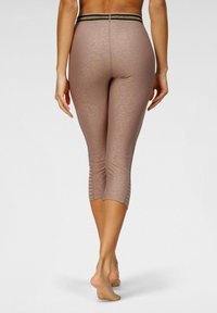 Leggings capri marroni con una sottile stampa leopardata, caratterizzati da una vita elastica nera e dorata e dettagli in rete trasparente sui lati inferiori.
