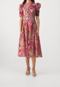 Vestido midi floral en tonos rosa y multicolor, con mangas abullonadas, una cintura ajustada y una tela ligera y fluida. Con un diseño plisado como detalle.