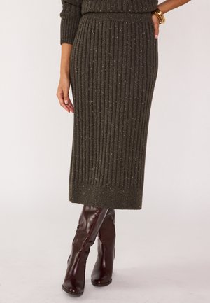 Olijfgroene gebreide midi-skirt met goudkleurige speckles, elastische tailleband en een rechte snit, gecombineerd met bordeauxrode kniehoge laarzen.