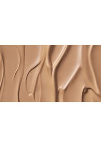 Base líquida en un tono beige cálido, con una textura suave y fluida y un ligero brillo, creando patrones suaves y ondulantes.