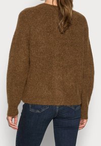 Brun stickad tröja med en lös, avslappnad passform, rund halsringning och långa ärmar, med en mjuk textur och något kortare längd.