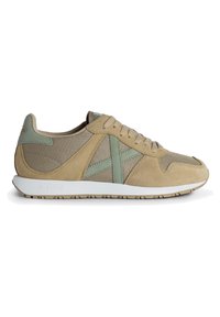 Zapatilla beige con paneles de malla y acentos de ante en verde claro. Cuenta con una suela texturizada y cordones beige, diseñada para ofrecer comodidad y estilo.