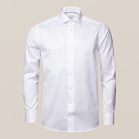 Vit långärmad skjorta av slät tyg med klassisk krage, framknäppning och enkelknäppning vid ärmarna.