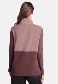 Fleece jacket in light pink and dark brown, featuring a high collar and color-block design with smooth texture.